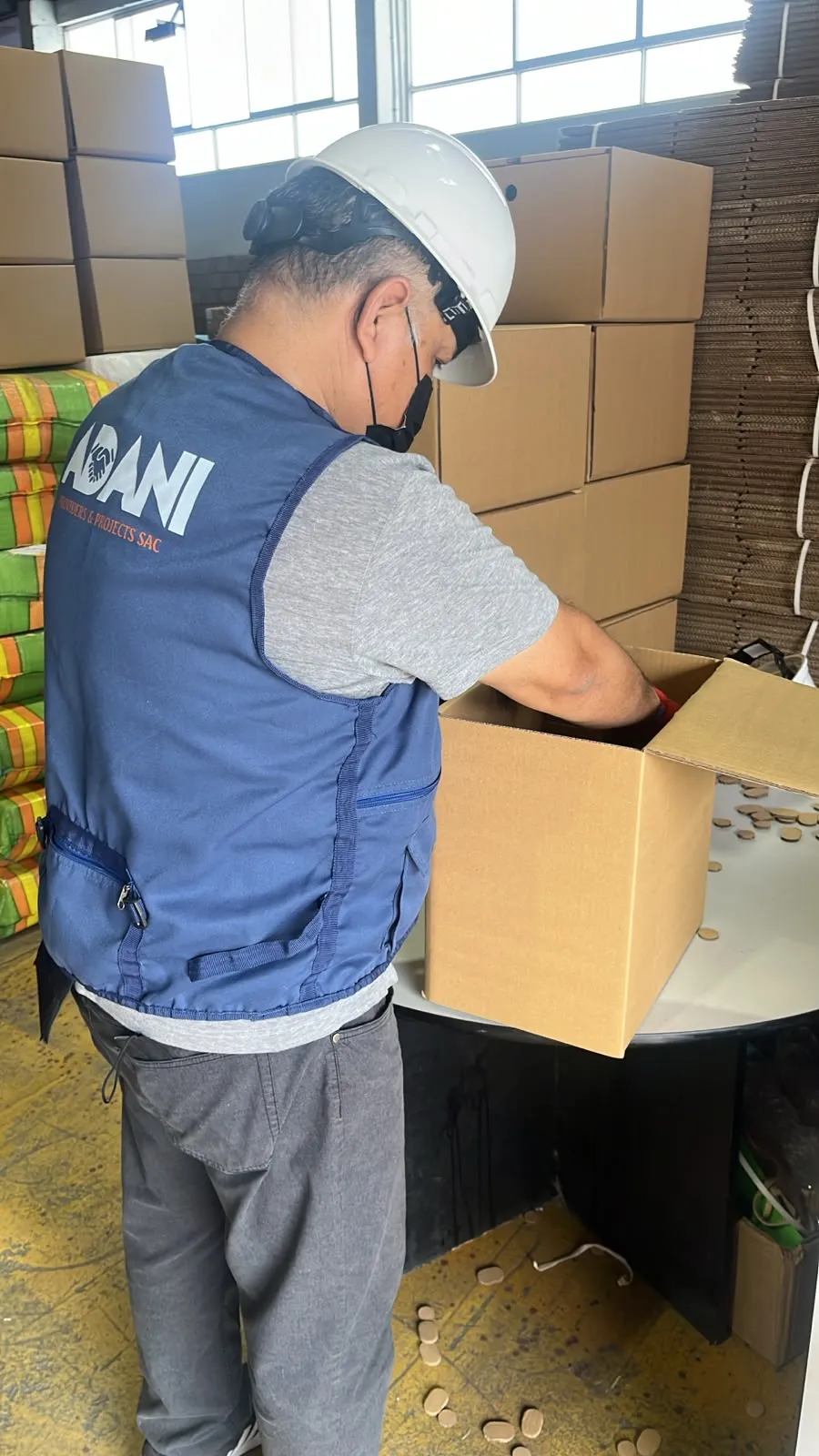 Colaborador de ADANI, con chaleco de la empresa, organizando documentos en cajas de archivo