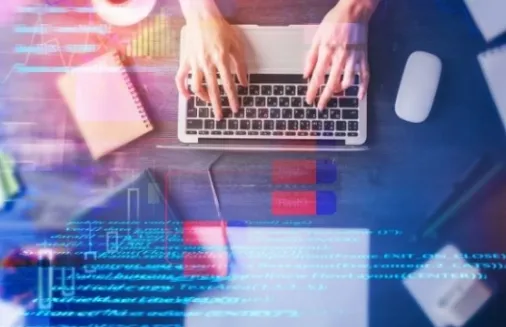 Persona trabajando en una laptop con documentos y datos digitales